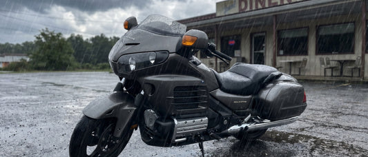Motorcycle seat rain cover need shown by Honda Gold Wing parked in summer downpour with soaked factory vinyl seat