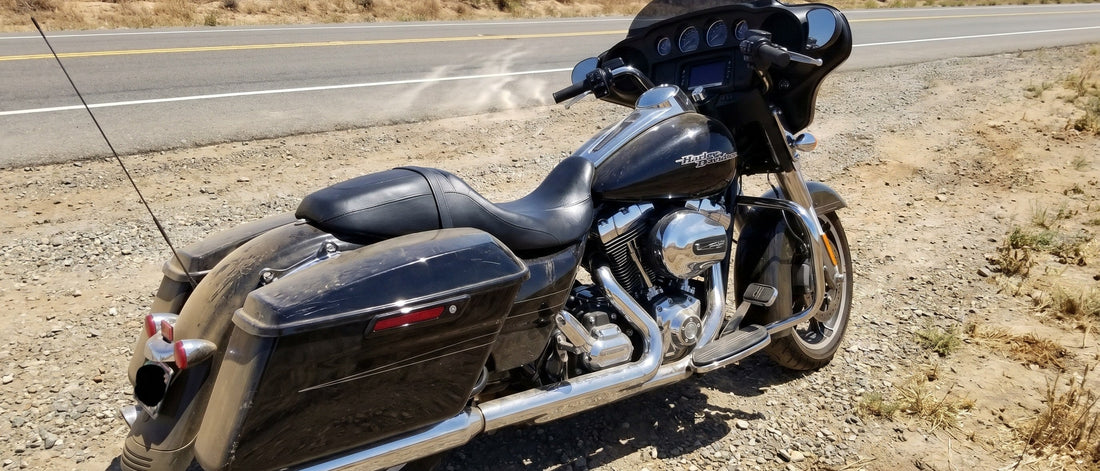 Sheepskin motorcycle seat cover question shown on Harley Street Glide parked on shimmering summer highway